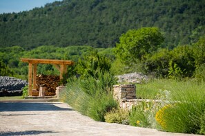 A paved pathway leading to a wooden pergola with a stone wall and greenery. - Stylish Villa in Lovreč with Sauna (Opanci)