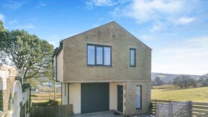 A two-story stone house with a garage, a small front porch, and a fenced yard. - 2 Bed in Barrowford (oc-w30592) (Barrowford)