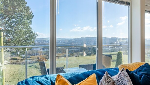 A room with a large window overlooking a landscape, a sofa with cushions, and a glass railing. - 2 Bed in Barrowford (oc-w30592) (Barrowford)