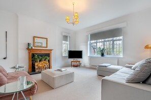 A living room with a fireplace, sofa, ottoman, television, and a large window. - 2 Bed in Eastbourne (oc-b30385) (Eastbourne)