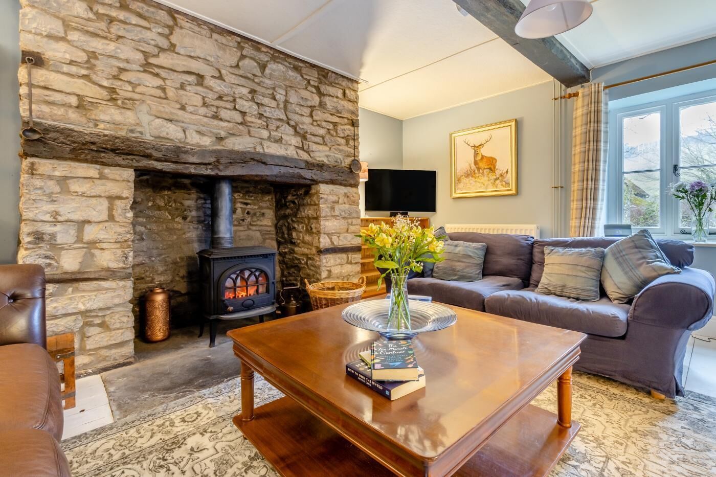 A cozy living room with a stone fireplace, a comfortable sofa, a wooden coffee table, and a television.