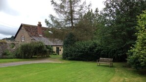 A stone house with a brick chimney, surrounded by a well-maintained lawn and dense shrubbery. - 6 Bed in Lower Chapel (oc-c30673) (Lower Chapel)