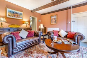 Ein möbliertes Wohnzimmer mit einer Couch, Sesseln, einem Couchtisch und einem Teppich mit Muster.