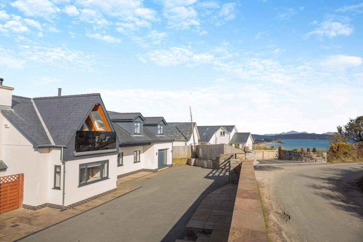 A coastal residential area with houses featuring gabled roofs and a clear view of the sea.