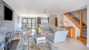 A spacious living area with a dining table, sofa, and staircase. - 5 Bed in Bwlchtocyn (oc-s30770) (Bwlchtocyn)