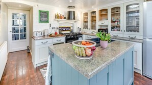 Een moderne keuken met witte kastjes, granieten aanrecht en een centraal eiland met een fruitschaal.