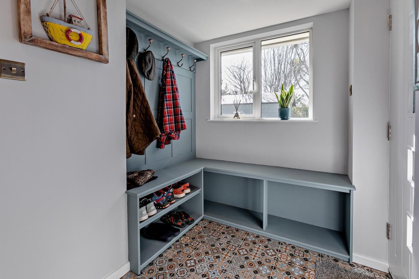 A corner room with a bench, coat hooks, and a window with a view.