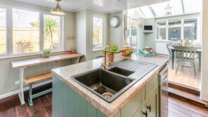 Een keuken met een groot eiland, een houten bank en potplanten.