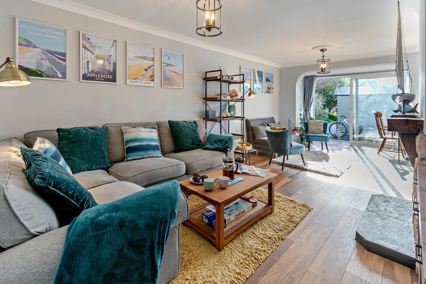 A modern living room with a grey sofa, teal cushions, a wooden coffee table, and a bookshelf.