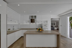 A modern kitchen with white cabinetry, a central island, and a fruit bowl. - Luxury Villa in Baška Voda (Baška Voda)