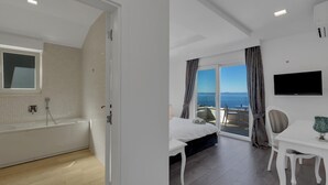 Een moderne hotelkamer met een badkuip, een bed, een bureau en een televisie.