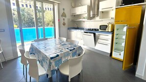 Una cucina con tavolo e sedie, un forno a microonde, un fornello e un frigorifero.