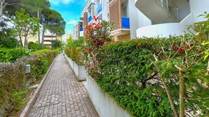 Un sentiero conduce a moderni edifici residenziali con balconi, immersi nel verde.