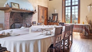 Un comedor con chimenea de ladrillo, techo de madera y amplios ventanales.
