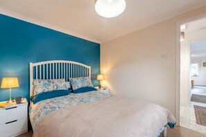 Ein Schlafzimmer mit einem Bett, Nachttischen und einer Tür zu einem anderen Raum.