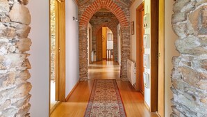 A hallway with stone walls, wooden flooring, and a patterned rug.