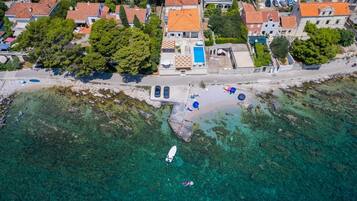 Luchtbeeld van een kustgebied met huizen, een strand en helder water.