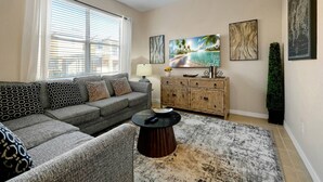 Una sala de estar con un sofá gris, una mesa de centro y un mueble con objetos decorativos.