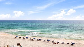 Een strand met parasols en ligstoelen langs de waterlijn.