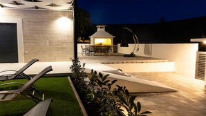 Eine moderne Außenpatio mit Grillbereich, Sitzgelegenheiten und einem gepflegten Rasen.