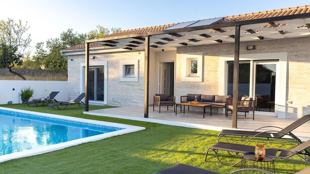 Ein modernes Haus mit Schwimmbad, Sitzgelegenheit im Freien und einer Pergola.
