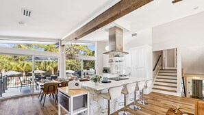 A modern kitchen with a large island, white cabinetry, and a view of the outdoors. - Spacious Family Retreat w/ Pool, LSV, 7 Bikes, & Generous Outdoor Space w/BBQ (Dune Allen)