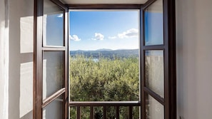 A window with a view of a mountainous landscape and dense greenery. - Spartilas Villas (Corfu)