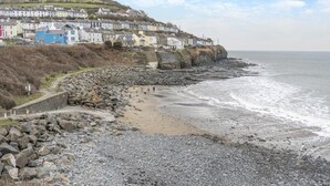 Uma vila costeira com casas em socalcos, uma praia rochosa e vista para o mar.
