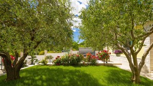 A well-maintained garden with a lawn, trees, and flowering shrubs. - Tranquil Country Villa in Naklice (županija,)