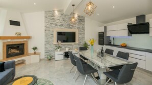 A modern kitchen with a dining area, built-in appliances, and a stone accent wall. - Tranquil Country Villa in Naklice (županija,)