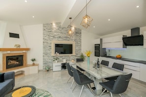 A modern kitchen with a dining area, built-in appliances, and a stone accent wall. - Tranquil Country Villa in Naklice (županija,)