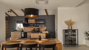 A modern kitchen with wooden cabinetry, a central island, and a dining area with a wooden table and black chairs.