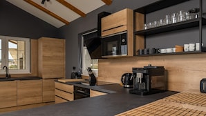 A modern kitchen with wooden cabinets, a black countertop, a coffee machine, and a microwave.