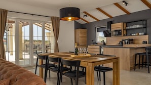 A modern kitchen with a wooden island, black chairs, and a hanging light fixture.