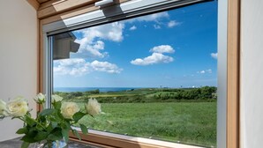 A window with a clear view of a green field and a blue sky with clouds. - 3 Bed in Stibb (oc-s30912) (Stibb)