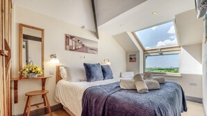 A bedroom with a bed, a nightstand, a window with a view, and a painting on the wall. - 3 Bed in Stibb (oc-s30912) (Stibb)