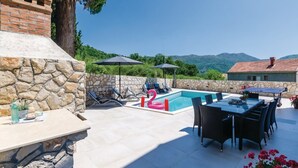 A poolside area with stone walls, a swimming pool, lounge chairs, and a table with chairs. - Zaton Family Getaway near Adriatic Sea (Zaton)