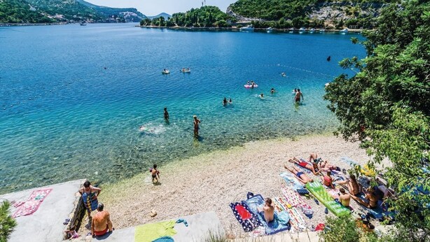 A beach with clear water, people swimming and sunbathing, and a view of the surrounding hills. - Zaton Family Getaway near Adriatic Sea (Zaton)