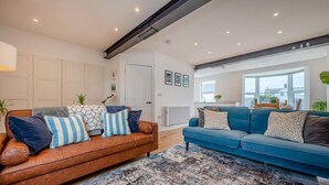 A living room with two sofas, a patterned rug, and a view of the kitchen through an open door. - 3 Bed in Bude (oc-t30908) (Bude)