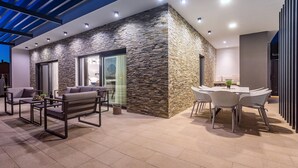 An outdoor patio area with a stone wall, seating, and a dining table. - Luxury Villa Retreat in Šestanovac (Šestanovac)