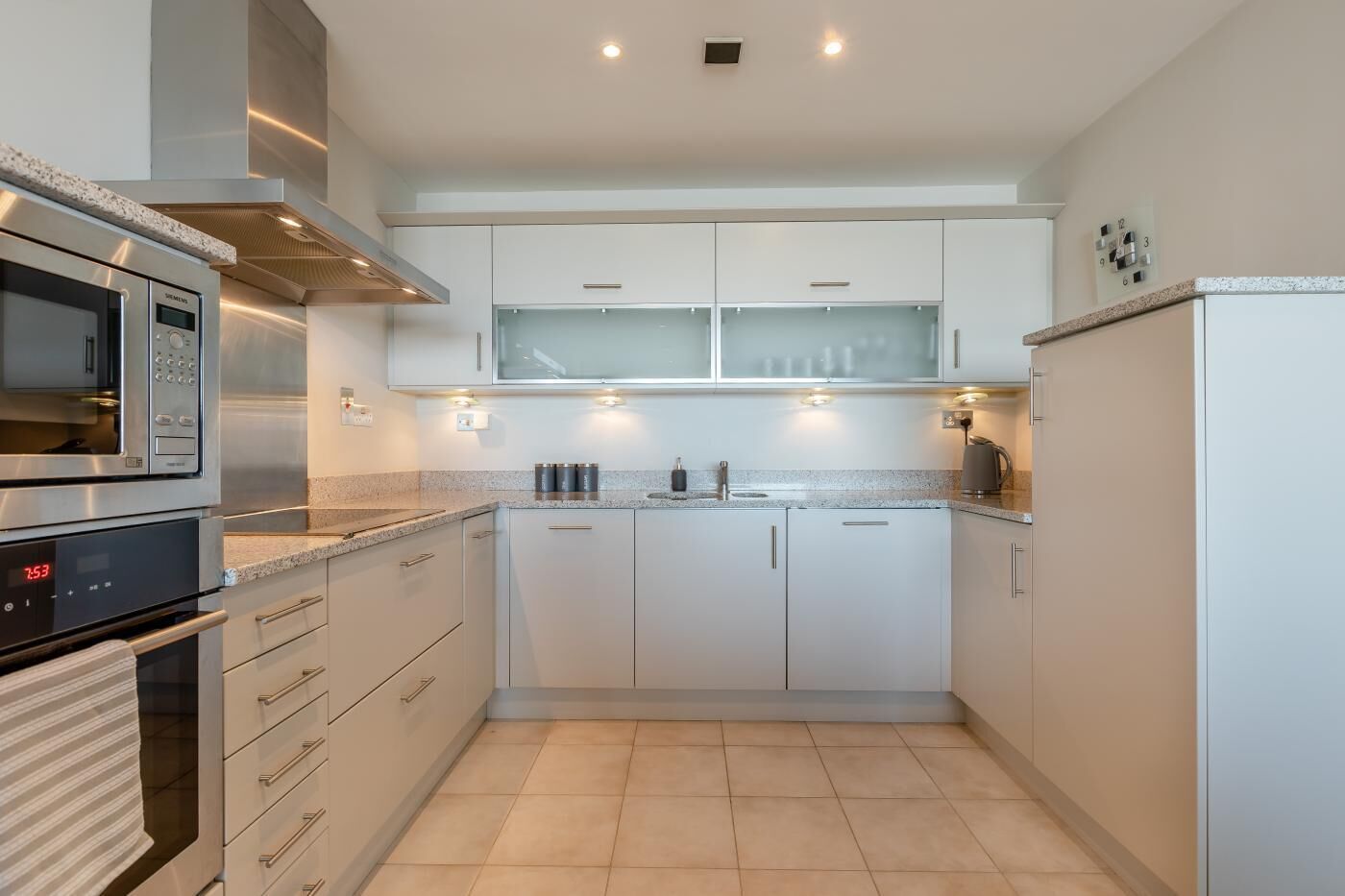 A modern kitchen with white cabinetry, a built-in microwave, a stove, and a refrigerator.