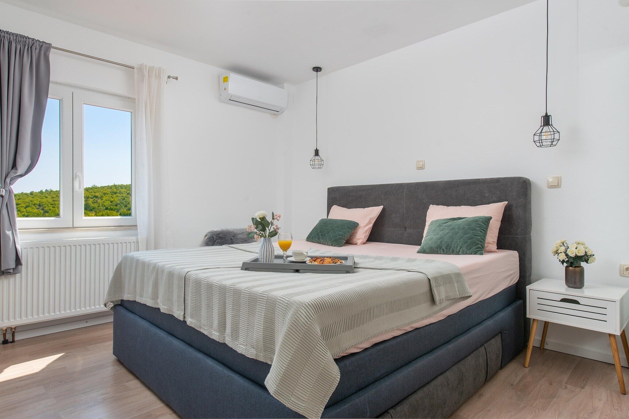 Un dormitorio con cama, mesita de noche y ventana con cortinas.
