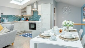 Een moderne keuken met dakraam, witte kasten en een blauwe achterwand.