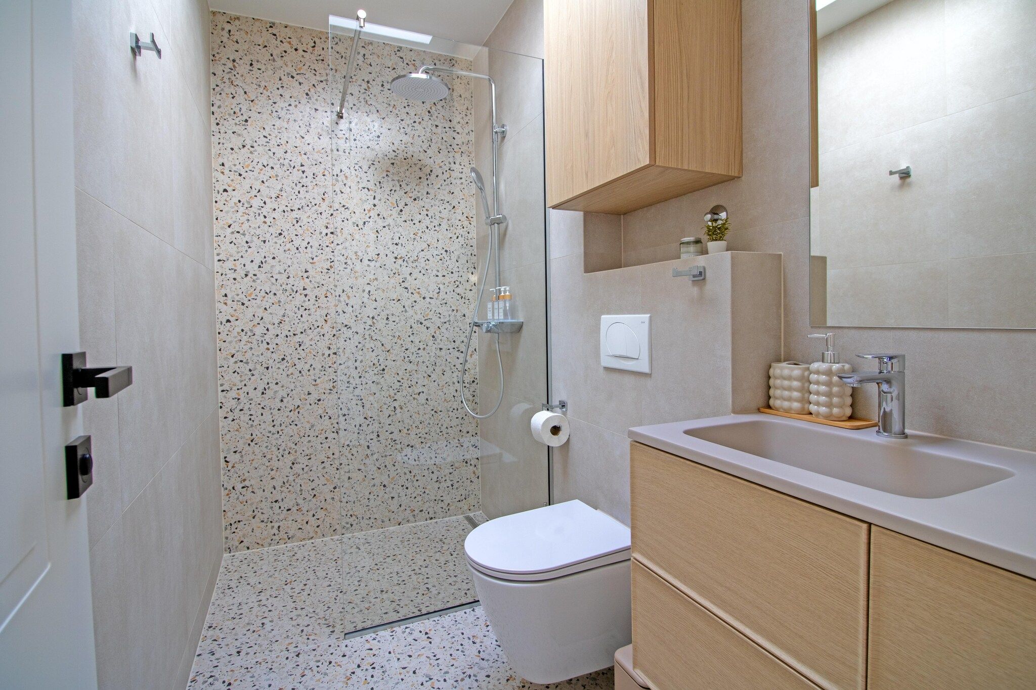 Ein Badezimmer mit Dusche, Toilette, Waschbecken und Holzschränken.