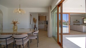 A modern dining area with a glass table, chairs, and a decorative vase. - Beach Villa with pool near Split (Split-Dalmatia County,)