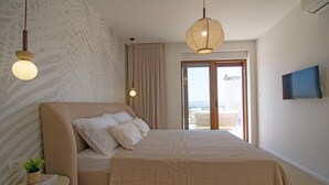 A bedroom with a large bed, a TV mounted on the wall, and a view through the door. - Beach Villa with pool near Split (Split-Dalmatia County,)