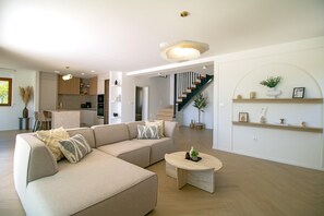 Ein modernes Wohnzimmer mit Ecksofa, Couchtisch und einer Treppe, die in einen oberen Bereich führt.