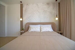 Ein Schlafzimmer mit einem großen Bett, zwei Nachttischen, einer Wand mit einem Blattmuster und zwei Pendelleuchten.