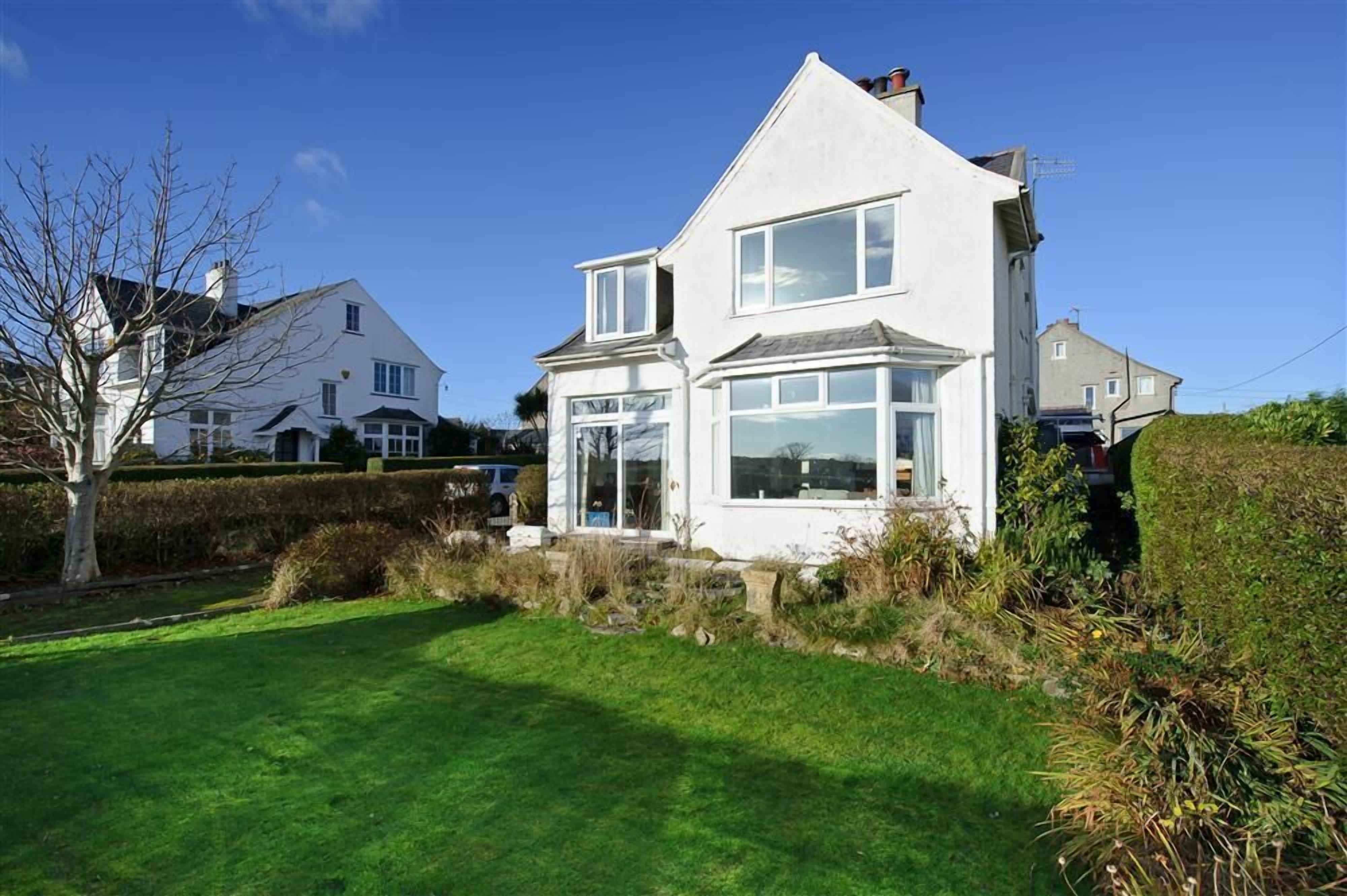 A two-story house with a well-maintained lawn and a clear blue sky.