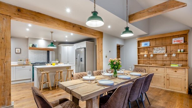 Un espace repas avec une table en bois dressée pour six personnes, entourée de chaises rembourrées.
